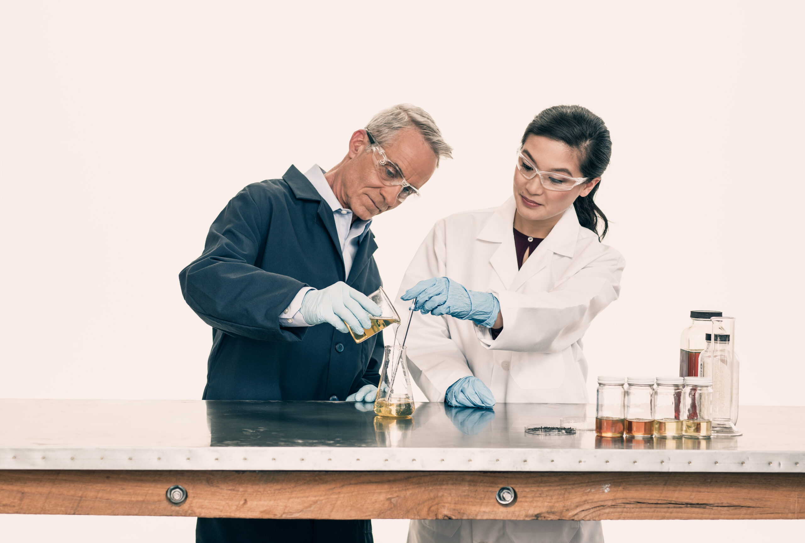 Male and female scientists pouring a chemical into a beaker